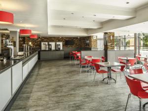 ein Restaurant mit roten Stühlen und Tischen in einem Raum in der Unterkunft ibis Hull City Centre in Hull