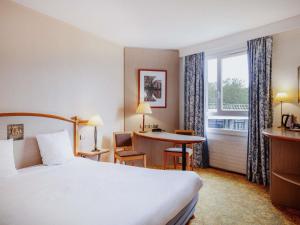 a hotel room with a bed and a desk and a window at Mercure Nevers Pont De Loire in Nevers