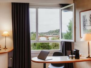 un bureau avec une fenêtre et un bureau avec un ordinateur portable dans l'établissement Mercure Nevers Pont De Loire, à Nevers