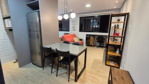 Una cocina y un comedor con una mesa y un refrigerador. en Studio Aconchegante Jd Botânico, en Curitiba