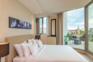 a bedroom with a large white bed and a large window at NH Collection Budapest City Center in Budapest
