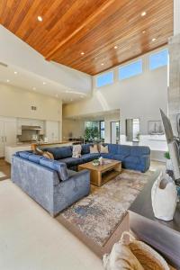 Una gran sala de estar con sofás azules y un techo de madera. en Luxury Stay with Pool, Spa, Fire Pit, Outdoor Lounge & Stunning Ocean Views, Encinitas Retreat, en Green Valley Mobile Estates