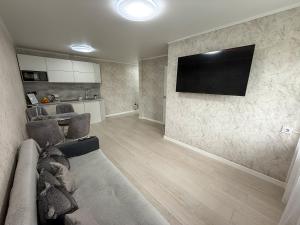 ein Wohnzimmer mit Couch und Flachbildfernseher in der Unterkunft 1-комнатная квартира в центре на 1 Мая 81 in Qostanai