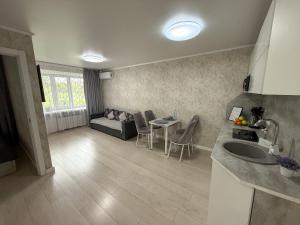 eine Küche und ein Wohnzimmer mit einer Couch und einem Tisch in der Unterkunft 1-комнатная квартира в центре на 1 Мая 81 in Qostanai