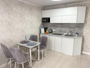 eine Küche mit weißen Schränken und einem Tisch und Stühlen in der Unterkunft 1-комнатная квартира в центре на 1 Мая 81 in Qostanai + 12 Fotos
