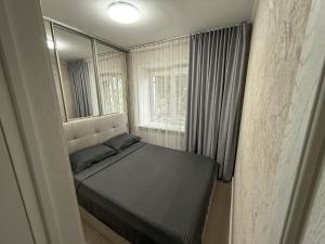 ein kleines Schlafzimmer mit einem Bett und einem Fenster in der Unterkunft 1-комнатная квартира в центре на 1 Мая 81 in Qostanai