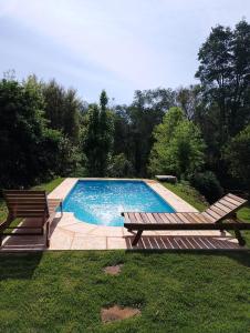 a swimming pool with two wooden benches next to it at Casa de la Guayubira in El Soberbio