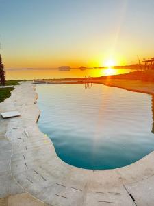 einen Pool mit Wasser und Sonnenuntergang im Hintergrund in der Unterkunft Breezy island Hotel in Siwa