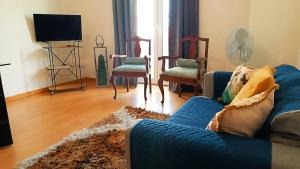 un soggiorno con un divano e sedie blu di Gardunha Apartments Avenida V a Fundão