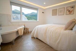 a bedroom with a bed and a tub and a window at Sea Donard Apartment, Newcastle in Newcastle