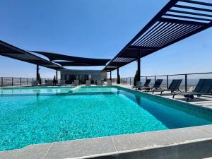 a swimming pool with chairs and an umbrella at Depa con alberca cerca de Andares y Landmark in Guadalajara