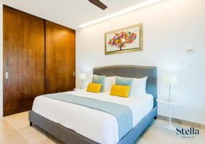 ein Schlafzimmer mit einem großen Bett mit zwei gelben Kissen in der Unterkunft Condos with Private Jacuzzi and shared Ocean View Roof pool in Playa del Carmen