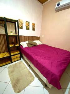 a bedroom with a bed with a purple blanket at Meu aconchego - check-in e checkout flexível in Belém
