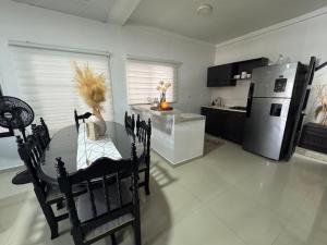 a kitchen with a table and a stainless steel refrigerator at Casa bonita y cómoda con antejardín Barrio Jardín 2-4 personas in Leticia