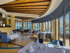 a dining room with tables and chairs and windows at Novotel Bahrain Al Dana Resort in Manama