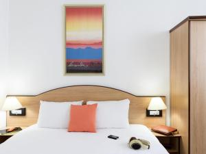 a bed in a hotel room with a picture on the wall at Résidence Studio Genève Centre in Geneva