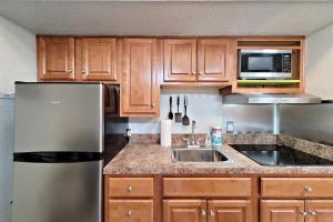 een keuken met houten kasten en een roestvrijstalen koelkast bij Pirates Cove Condo Unit #401 in Halifax Estates +31 foto's