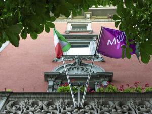 two flags flying in front of a pink building at Mercure Bergamo Centro Palazzo Dolci in Bergamo
