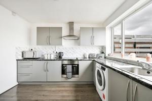 a white kitchen with a sink and a dishwasher at Modern 3-Bed Maisonette - Epping High Street - Parking - LMV Property in Epping +37 photos