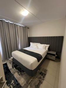 una camera da letto con un letto grande con lenzuola bianche di AmeAnele Homes a Gaborone