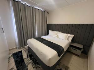 una camera da letto con un letto con lenzuola e cuscini bianchi di AmeAnele Homes a Gaborone