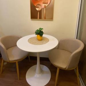 een witte tafel met twee stoelen en een potplant erop bij La Mari 1 bedroom at Prisma Residences in Manilla