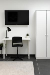 a desk with a chair and a television on a wall at Skylight Studio Kastel in Wiesbaden