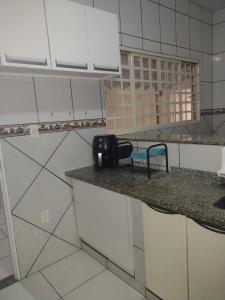 a kitchen with white cabinets and a counter top at Casa de temporada lus delicatte in Olímpia +10 photos