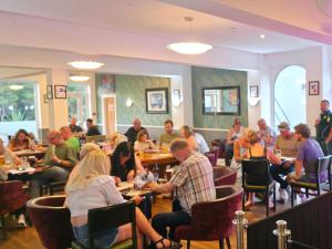 a group of people sitting at tables in a restaurant at The Springfield Hotel in Fairbourne