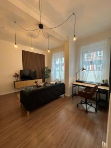 a living room with a couch and a desk and a television at Altstadt Apartment beim Schlossgarten in Schwerin