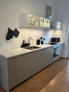 a kitchen with white cabinets and a sink at Altstadt Apartment beim Schlossgarten in Schwerin