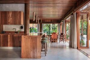 Una cocina con gabinetes de madera y un comedor. en Villa 21, en Itacaré