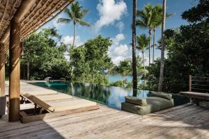 una piscina con terraza de madera y palmeras en Villa 21, en Itacaré