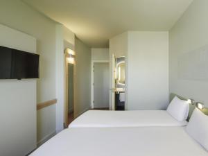 a bedroom with two beds and a flat screen tv at Ibis Budget Málaga Aeropuerto Avenida de Velazquez in Málaga +31 photos
