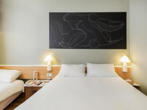 a bedroom with a large white bed with two lamps at Ibis Granada in Granada