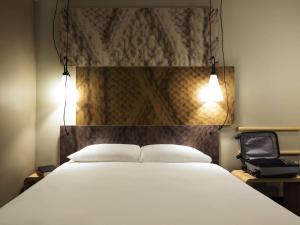 a bedroom with a large white bed with two lights at Ibis Den Haag City Centre in The Hague