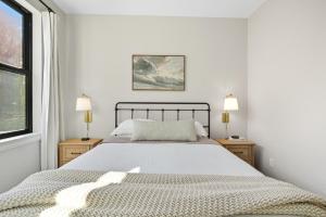 a white bedroom with a bed and two windows at Baby Birch Banks Guest House on Lake Pend Oreille in Sagle
