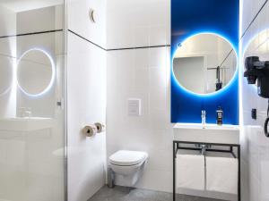 a bathroom with a toilet and a sink and a mirror at Hotel Ibis Krakow Centrum in Krakow