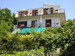 a white house with a balcony with flowers on it at Green Quiet Apartments in Vodice