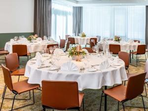 a conference room with tables and chairs with white tablecloths at Novotel Hamburg City Alster in Hamburg
