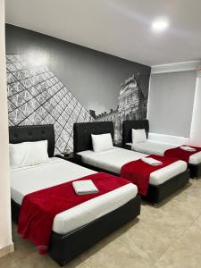 three beds in a room with a mural on the wall at Hotel Fenix in Cúcuta