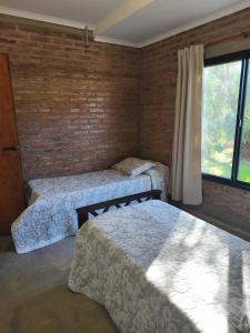Un dormitorio con dos camas y una pared de ladrillo. en Ale Siciliano, en General San MartÃ­n
