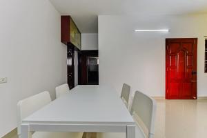 a white table and chairs in a room with a red door at Hotel O JJ Residency in Chennai +41 photos