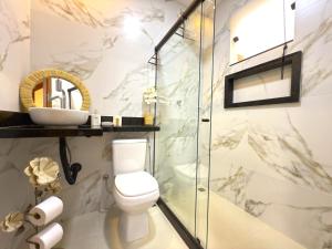 une salle de bain avec toilettes et douche en verre dans l'établissement Flat Centro de Buzios, à Búzios 30 autres photos