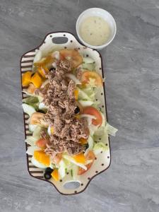 a plate of salad with meat and vegetables and a bowl of sauce at Smith Inn & Restaurant in General Luna