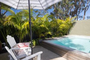 una silla y una sombrilla junto a la piscina en The Watermark, en Narrawallee