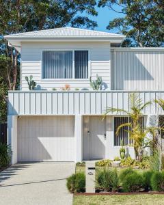 una casa blanca con garaje en The Watermark, en Narrawallee