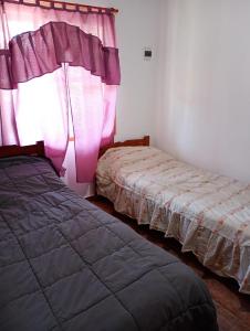 1 Schlafzimmer mit 2 Betten und einem Fenster mit rosa Vorhängen in der Unterkunft RuralEsquina in Esquina
