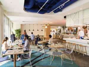 a group of people sitting at tables in a restaurant at Novotel Paris Centre Gare Montparnasse in Paris