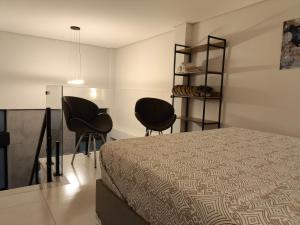 a bedroom with two chairs and a bed at Loft Tavares in Caparaó Velho